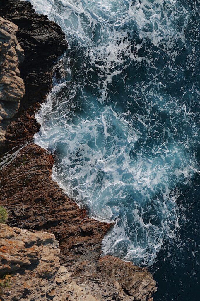 waves splashing on gray rocky cliff during daytime