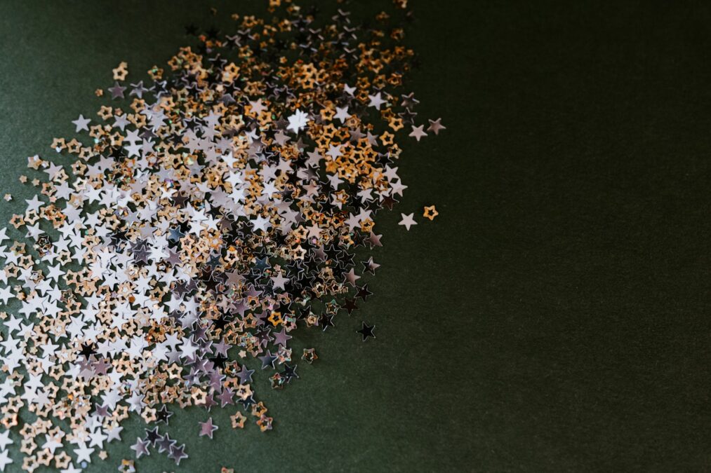 A pile of gold and silver stars on a green surface
