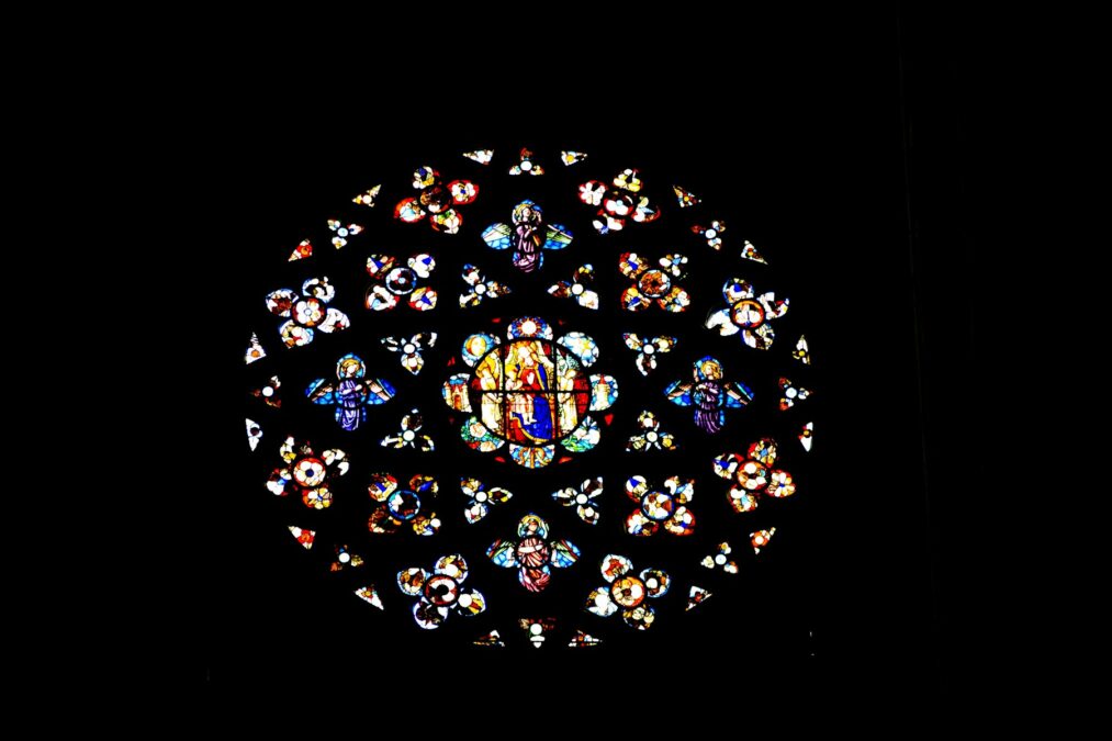 A large stained glass window in a dark room