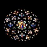 A large stained glass window in a dark room